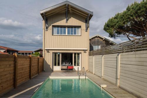 une maison avec une piscine en face d'une clôture dans l'établissement Superbe maison lumineuse, au calme avec piscine, à La Teste-de-Buch