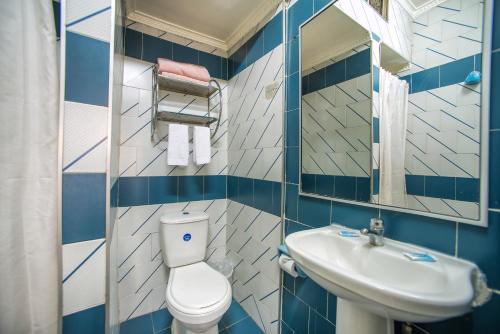 فندق Sahara Inn في سانتياغو: حمام ازرق وابيض مع مرحاض ومغسلة