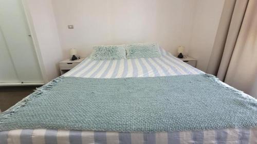 a bed with a blue and white comforter in a bedroom at Característico departamento 2 habitaciones, capacidad 4 y 5 personas, excelente vista de la ciudad y mar in Antofagasta