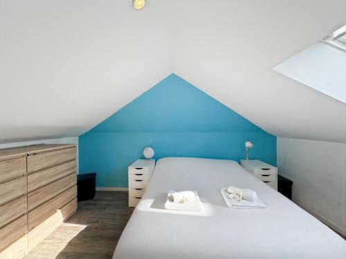 une chambre mansardée avec un lit et un mur bleu dans l'établissement Le Calypso - Duplex Paisible - Coeur de Saint Malo, à Saint-Malo