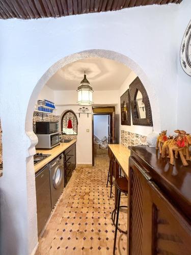 a kitchen with an archway with a table and a counter at Mog'ador bleue in Essaouira