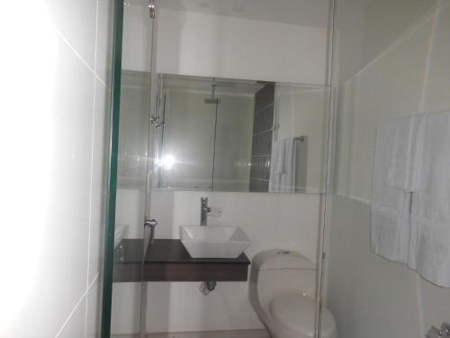 a bathroom with a sink and a toilet and a mirror at Massay Hotel in Neiva