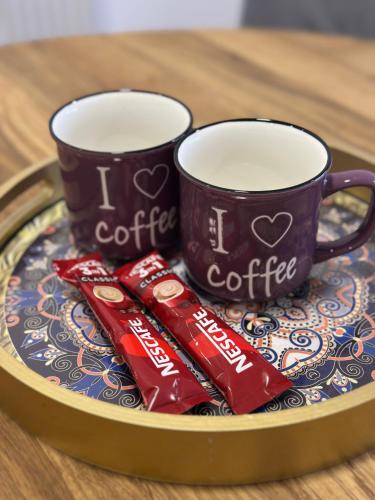 two coffee cups on a plate with chocolates at ZORA apartmani Sarajevo in Sarajevo