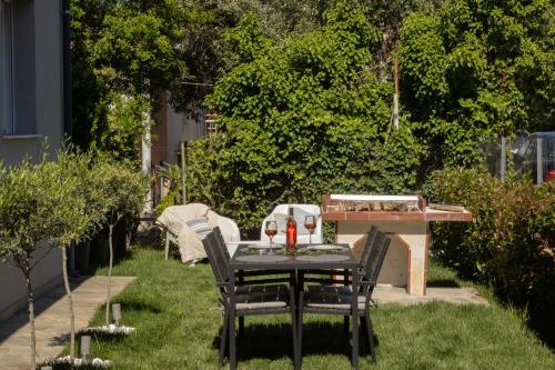 a table and chairs in a garden with a grill at Morfeas Residence in Chrysoupolis