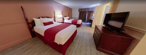a hotel room with two beds and a flat screen tv at Royal Suites Baton Rouge near LSU and Airport in Baton Rouge