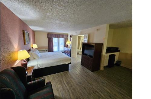 a hotel room with a bed and a flat screen tv at Royal Suites Baton Rouge near LSU and Airport in Baton Rouge