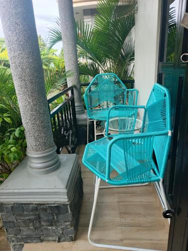 two blue chairs sitting on a porch next to a pole at Nsuube Apartment in Mukono