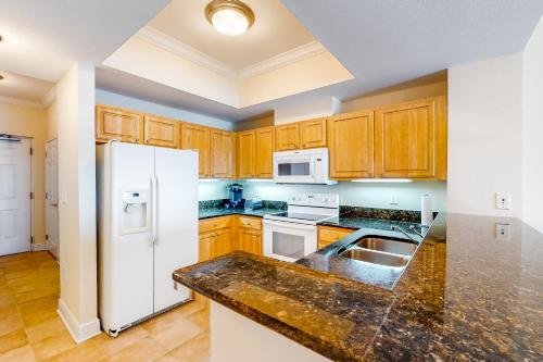 a kitchen with wooden cabinets and a white refrigerator at Crystal Tower 2006 in Gulf Shores
