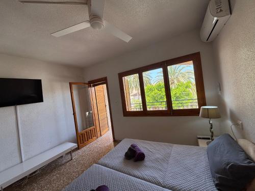 Un dormitorio con una cama y un televisor y una ventana. en Duplex adosado cerca de la playa puerto mazarron, en Puerto de Mazarrón