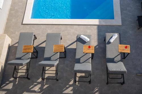 a group of chairs and tables next to a swimming pool at Pool and Breakfast Apartments Villa Maro in Novalja