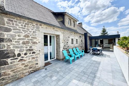 un patio avec des chaises bleues à côté d'un bâtiment en pierre dans l'établissement Longère de charme - Tout confort - 2min des plages, à Plouhinec