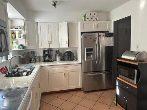 a kitchen with white cabinets and a stainless steel refrigerator at Bonitas habitaciónes in Pembroke Pines