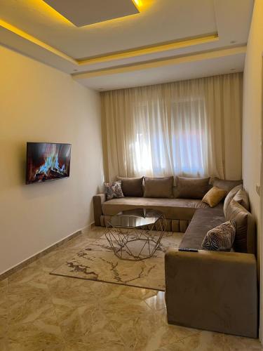 a living room with a couch and a tv on the wall at luxe appartement Nour D'asilah 1 WiFi 5G in Asilah
