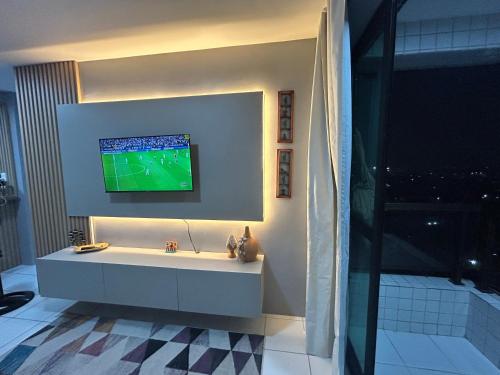a bathroom with a tv on the wall and a tub at Perfeito Ap Caruaru in Caruaru