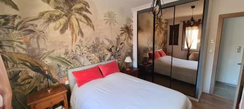 Cette chambre comprend un lit avec des oreillers rouges et une fresque murale. dans l'établissement Appartement ensoleillé Perols, à Pérols