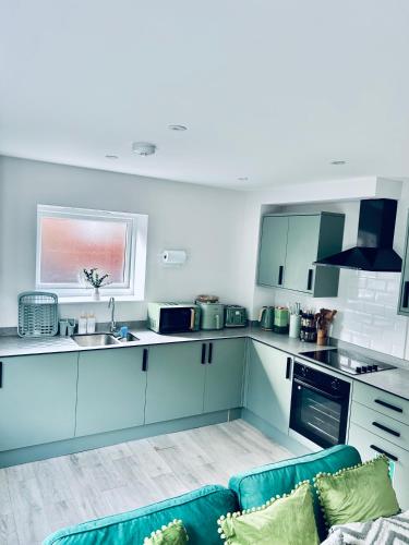 a kitchen with blue cabinets and a blue couch at Two Dover Ferry Apartments - sleep 8 with private terrace and castle views in Kent