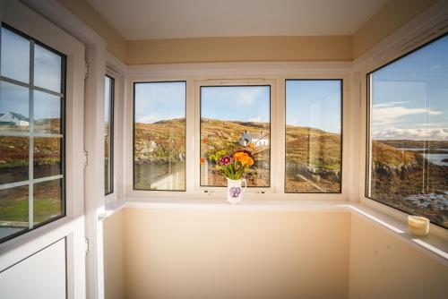 a window with a vase of flowers on a window sill at Sea Room, Scalpay in Scalpay