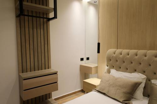 a bedroom with a bed with a headboard and a mirror at Apartments Romario in Sarandë