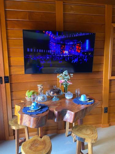 a wooden table with chairs and a tv on a wall at Chalé Vista da Mata in Rio Bananal
