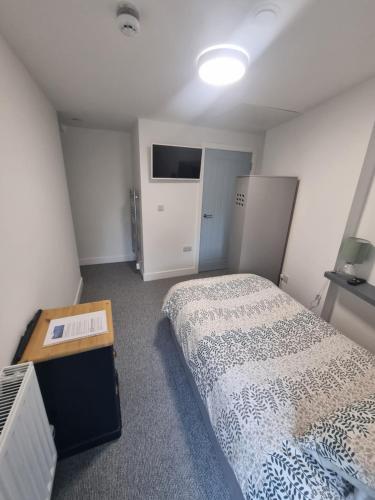a small bedroom with a bed and a table at Tanerdy - Professional units with shared communal areas in Carmarthen
