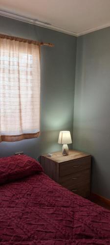 a bedroom with a bed and a lamp and a window at La Casita en Caldera in Caldera