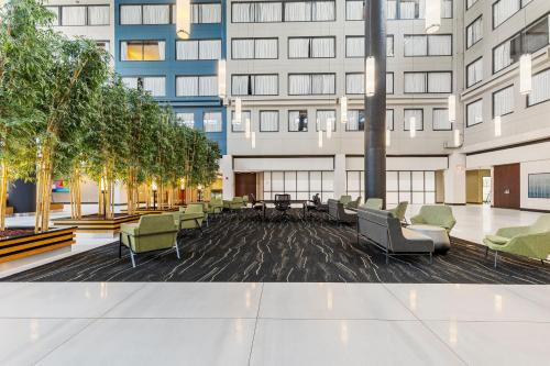 an empty lobby of a building with chairs and trees at The Armon Stamford Hotel & Conference Center in Stamford