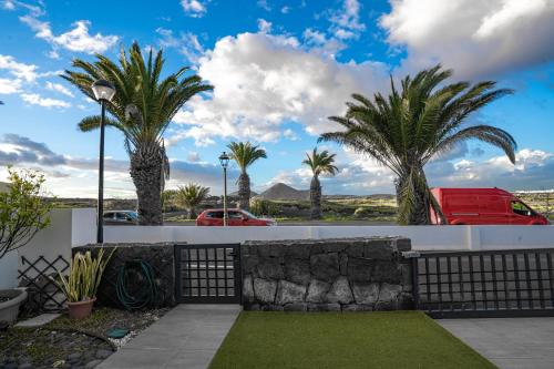 a retaining wall with palm trees and a red car at Casa Amy-Costa Teguise in Costa Teguise