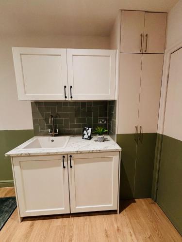a kitchen with white cabinets and a sink at Luxury standard flats in Central London, ideal for tourists in Northolt