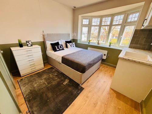 a bedroom with a bed and a dresser and windows at Luxury standard flats in Central London, ideal for tourists in Northolt