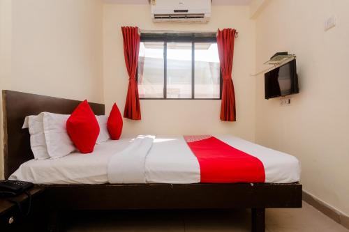 a bedroom with a bed with red pillows and a window at Hotel O Diplomat in Sopāra