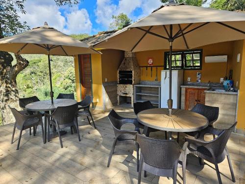 two tables and chairs with umbrellas on a patio at Vaca do Brejo, piscina aquecida, sauna, A/C quente in Petrópolis