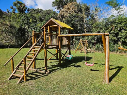 a wooden playground with a slide in a park at Vaca do Brejo, piscina aquecida, sauna, A/C quente in Petrópolis