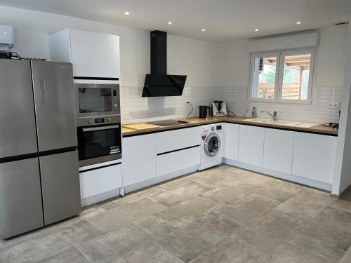 une cuisine avec des armoires blanches et une laveuse et une sécheuse dans l'établissement Chez lili, à Ghisonaccia