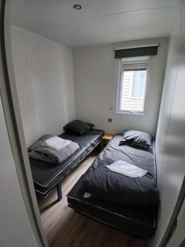 two beds in a small room with a window at Mobilhome dans les Pins in Seignosse