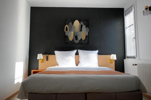 a bedroom with a large bed with a black wall at Hotel Le Gambetta in Bergerac