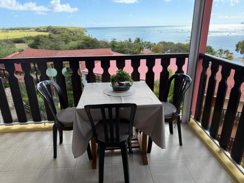 a table and chairs on a balcony with a view of the ocean at Appartement les pieds dans l’eau in Sainte-Anne