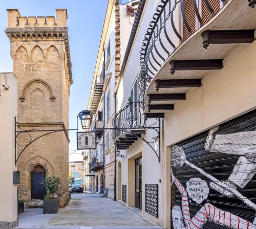 an alleyway between two buildings with a clock tower at Sette Fate Suites & Spa in Palermo