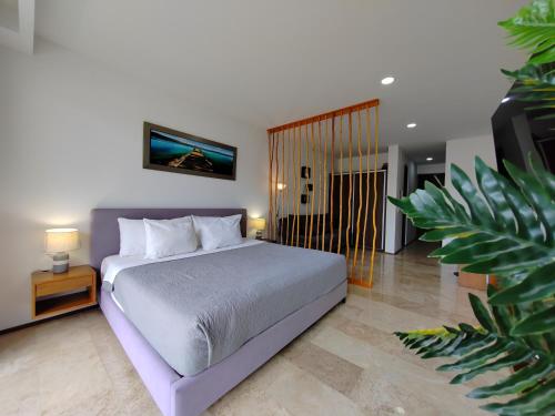 a bedroom with a large bed and a plant at Modernos Estudios a pasos De La 5ta Av Pool view - By Yeah in Playa del Carmen