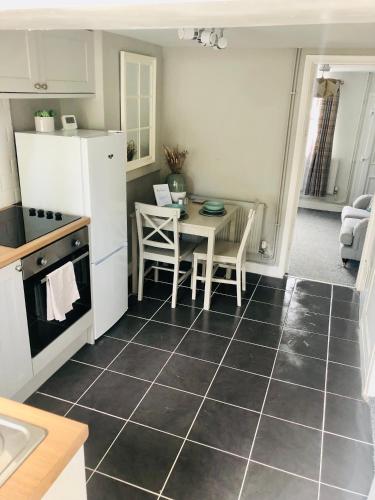a kitchen with a table and a white refrigerator at Beautiful, 1 Bedroom Cottage in Leicester