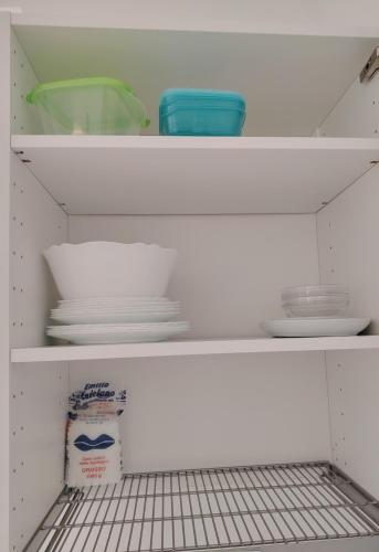 a white shelf with plates and bowls on it at Casa Polixeni - Da e Nònne in Carloforte