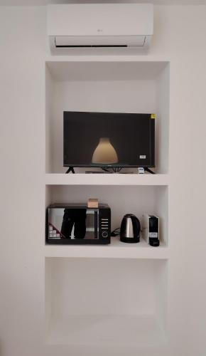 a shelf with a flat screen tv and a microwave at Casa Polixeni - Da e Nònne in Carloforte