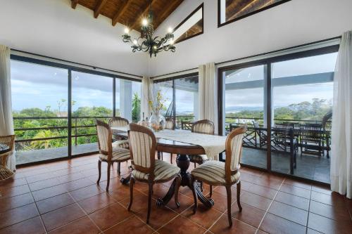 a dining room with a table and chairs and large windows at Casa das Hortências by Azoresrent in Farroupo