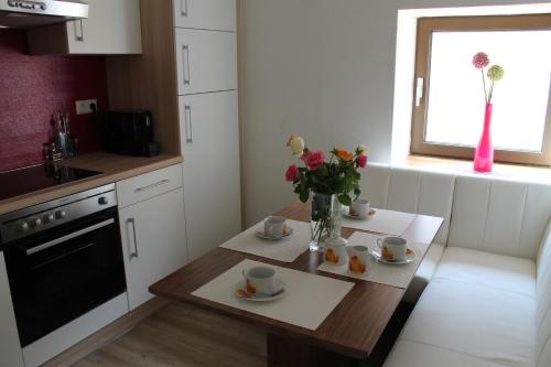 a kitchen with a table with cups and flowers on it at Post Hostel For Youth, Students and Pilgrims in Lavamünd