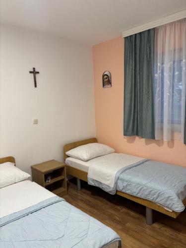a room with two beds and a cross on the wall at Casa Del Pellegrino M&A - Ostojići in Međugorje