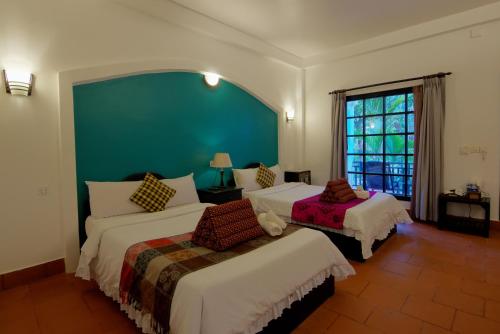 a bedroom with two beds and a green wall at Sonalong Boutique Village & Resort in Siem Reap