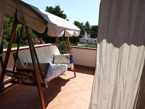 a porch with a bed and an umbrella at Alimede al Circeo in Borgo Montenero