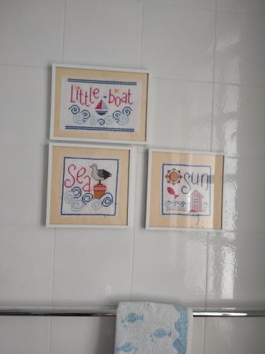 three framed pictures on a white wall with a chair at Alimede al Circeo in Borgo Montenero