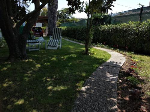 two chairs sitting in the grass next to a sidewalk at Alimede al Circeo in Borgo Montenero