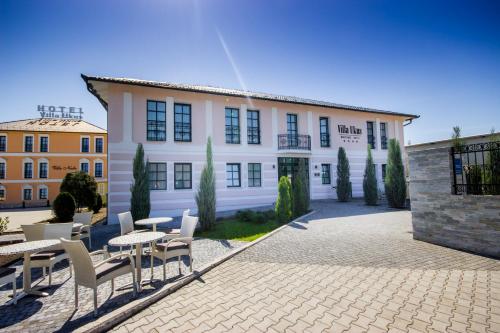 a building with tables and chairs in front of it at Boutique Hotel Ukus in Tešanj