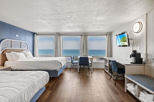 a hotel room with two beds and a desk at Seagull Beachfront Inn in Lincoln City